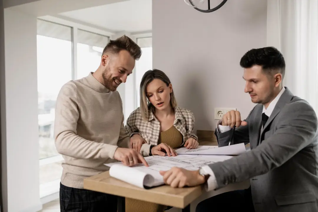 Three individuals examining paperwork collaboratively in an office environment.