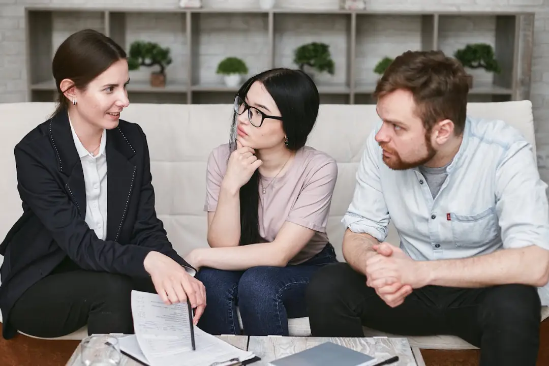 Three people engaged in conversation while sitting together on a couch